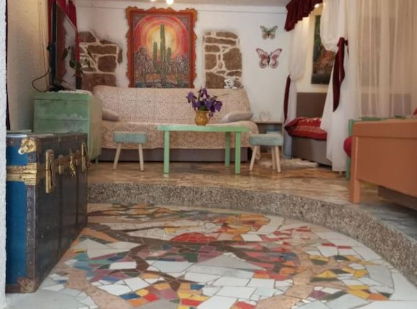 A cozy room with a sofa, a small table, a patterned rug, and a mosaic floor.