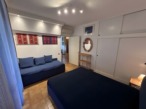 Ein Schlafzimmer mit Bett, Sofa, einem kleinen Tisch, einem Spiegel und einem Kleiderschrank.