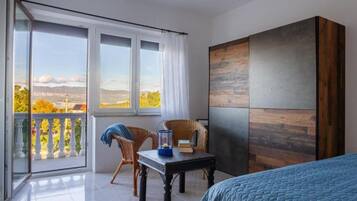 Ein Zimmer mit Bett, Tisch, Stuhl und Blick durch große Fenster.