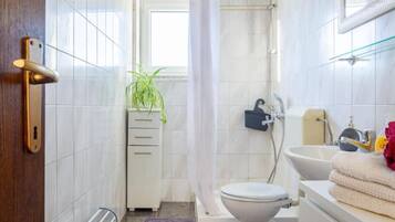 Ein Badezimmer mit Toilette, Bidet, Badewanne und einem kleinen Schrank mit Schubladen.