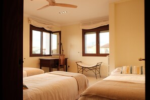 Un dormitorio con dos camas, un escritorio, una silla y ventanas amplias.