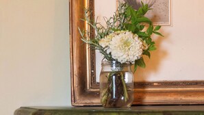 A framed illustration of a pitcher, a vase with flowers, and a decorative table with a curved leg. - Relais Monastero (Podenzano)
