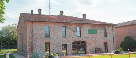 A brick building with a tiled roof, a sign reading 'BUTT,' and a paved area with benches.