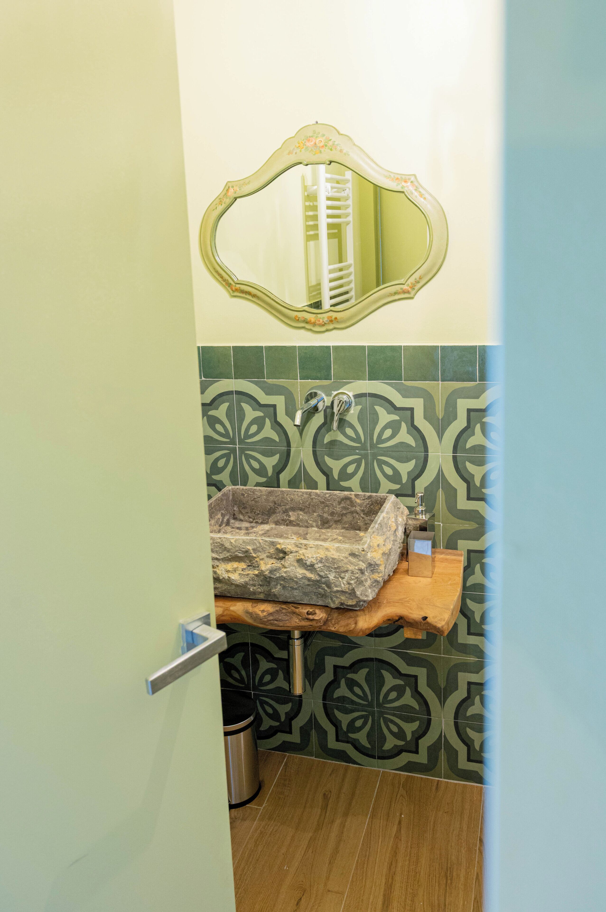 A bathroom with a sink, mirror, and patterned tiles.