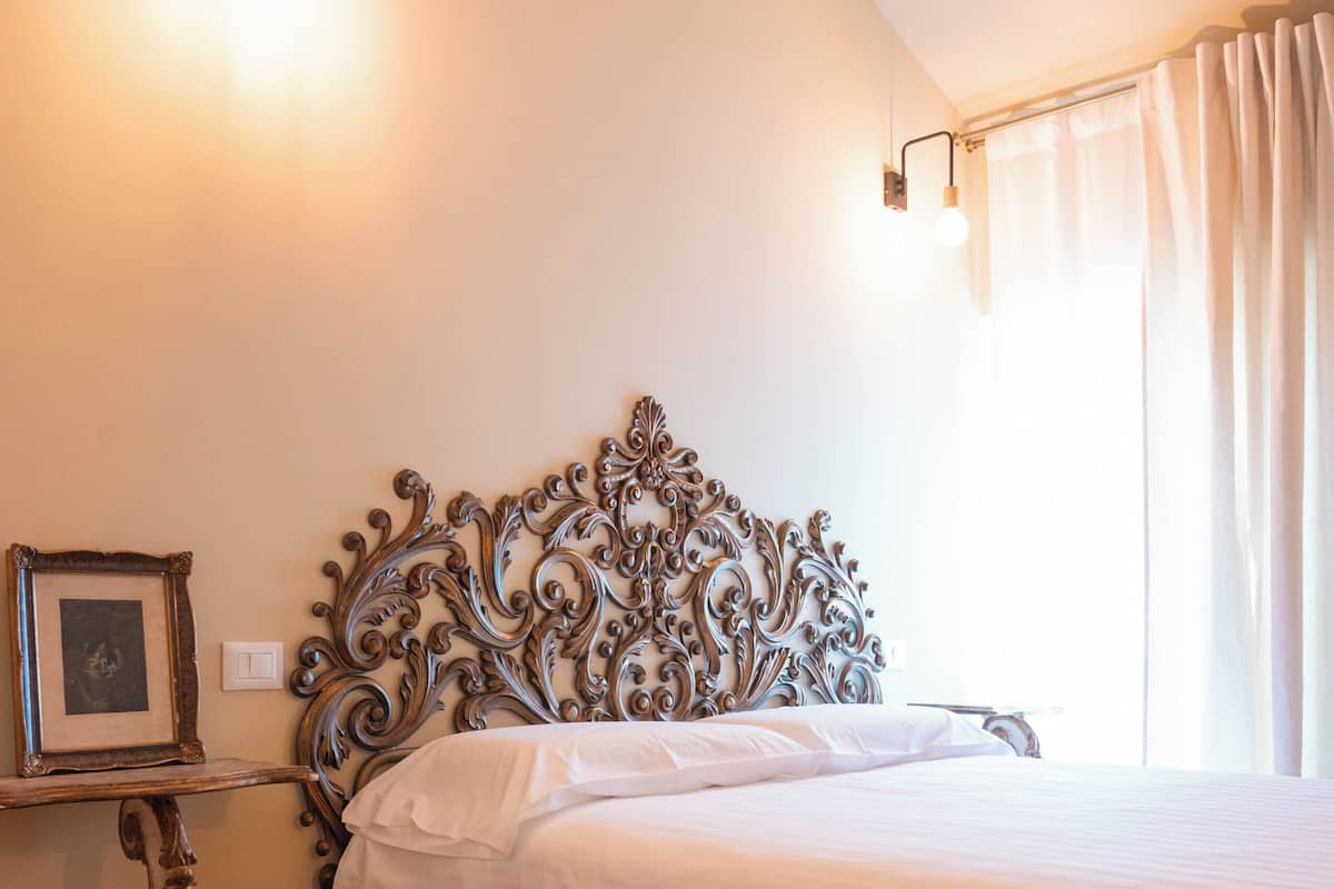 Un dormitorio con cabecero de madera, una mesita de noche y una lámpara de pared.