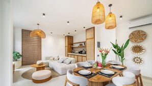 A modern living room with a dining area, wooden furniture, and decorative wall art. - Stella - Luxury Gateaway Villa  (Sayan)