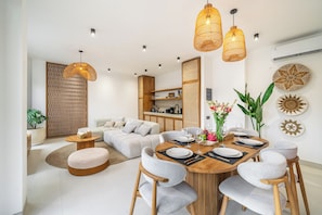 Una sala de estar moderna con comedor, muebles de madera y decoración en la pared.