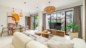 A modern living room with a sofa, dining table, chairs, and a TV. - Stella - Luxury Gateaway Villa  (Sayan)