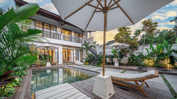 A poolside area with lounge chairs, umbrellas, and a two-story building with balconies. - Stella - Luxury Gateaway Villa  (Sayan)