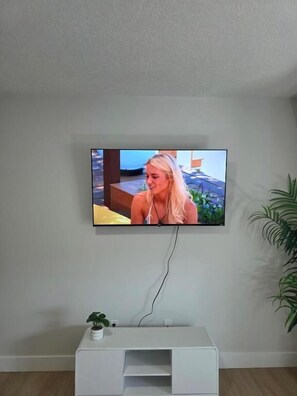 A television mounted on a wall with a white entertainment unit below it. - Cozy Irvine Creek Walk-out Suite 10 Mins to YEG (Leduc County)