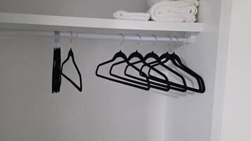 A closet with a white shelf holding folded towels and a row of black hangers.