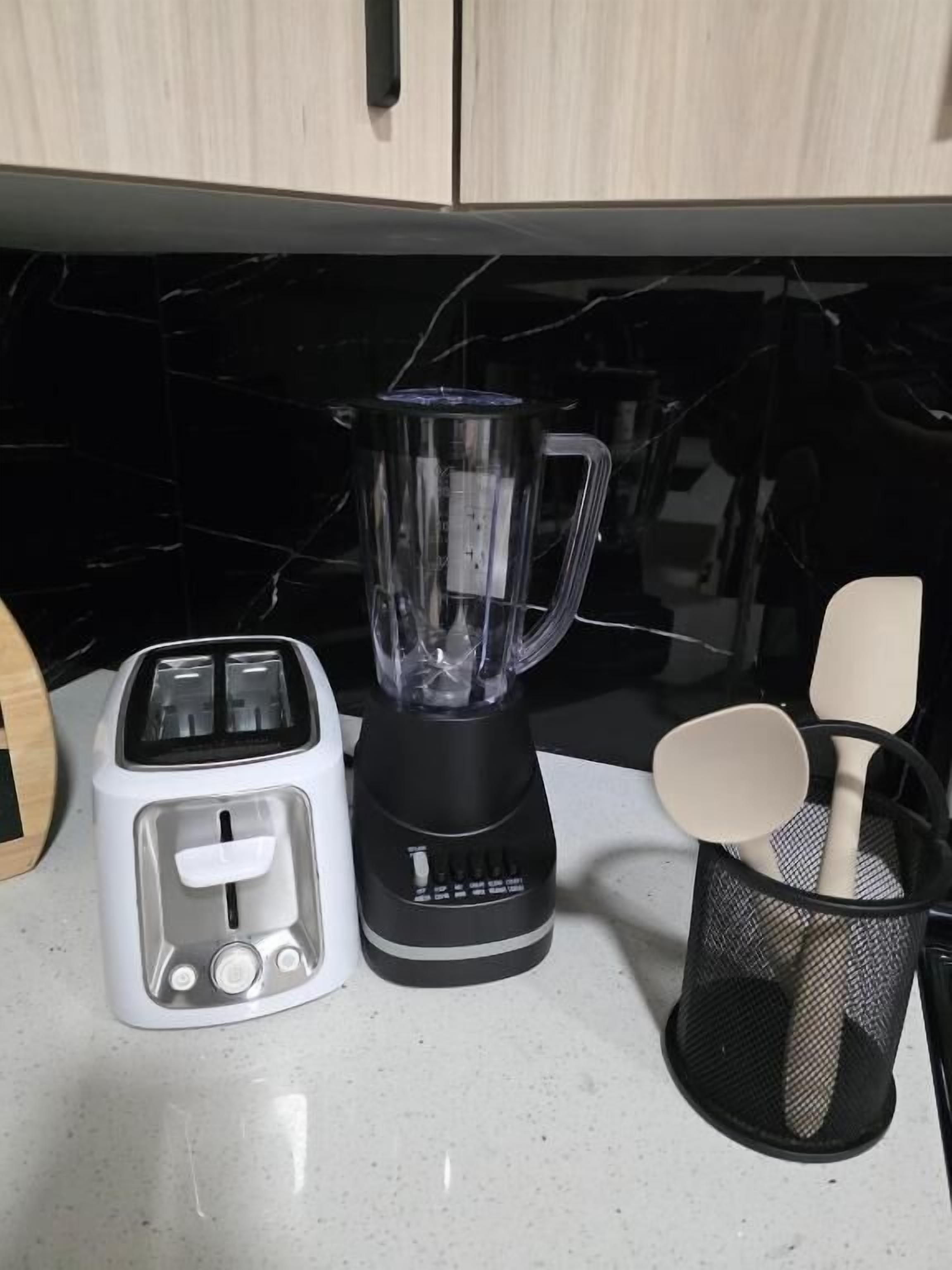 A kitchen counter with a toaster, a blender, and a utensil holder.