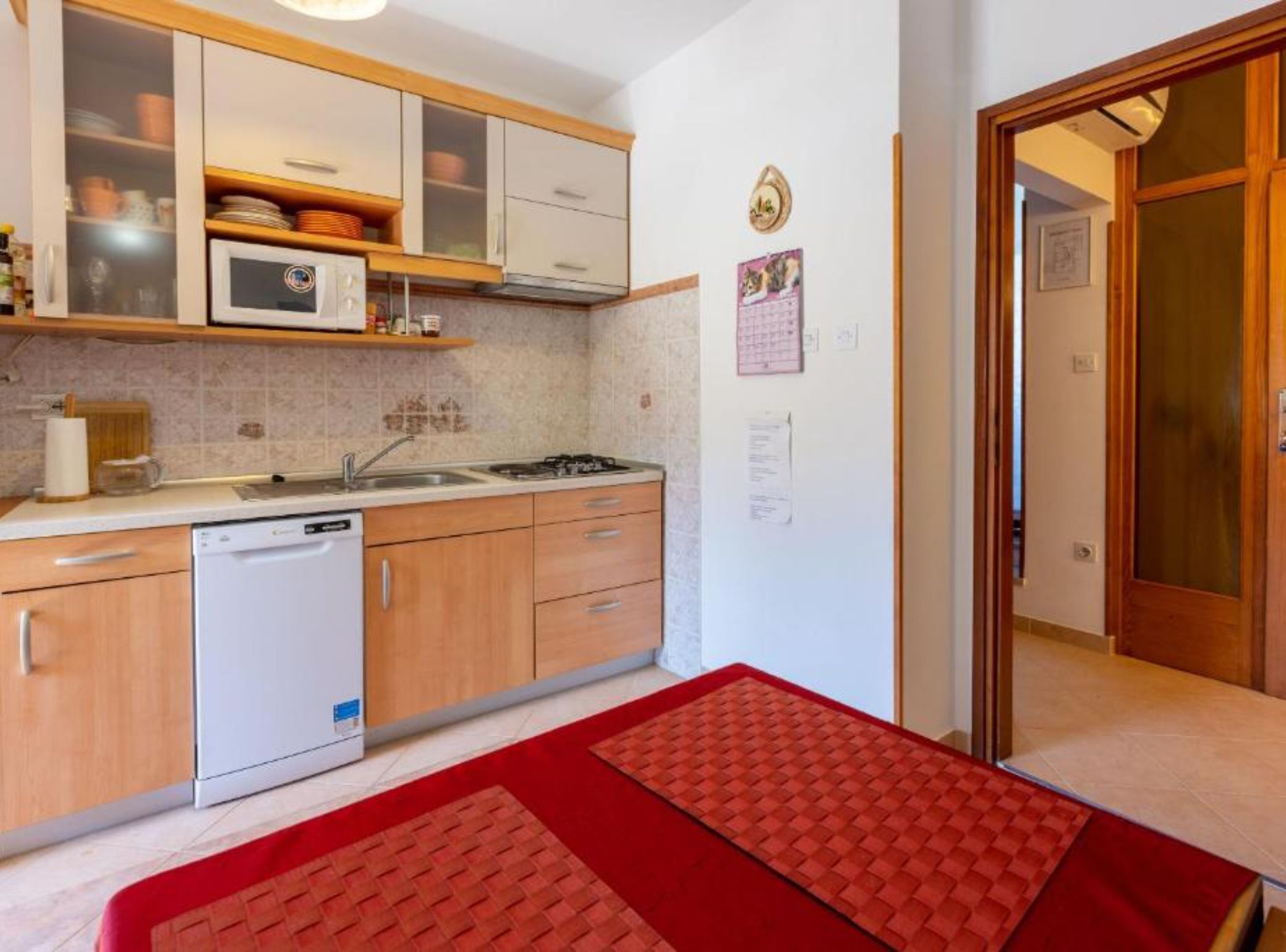 A compact kitchen with a dishwasher, microwave, and wooden cabinets.