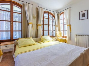 A bedroom with a bed, two bedside tables, a chair, and large windows with curtains. - Ma Vero Residence (Medulin)