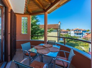 Un balcón con mesa y sillas, vista a casas vecinas y techo de madera.