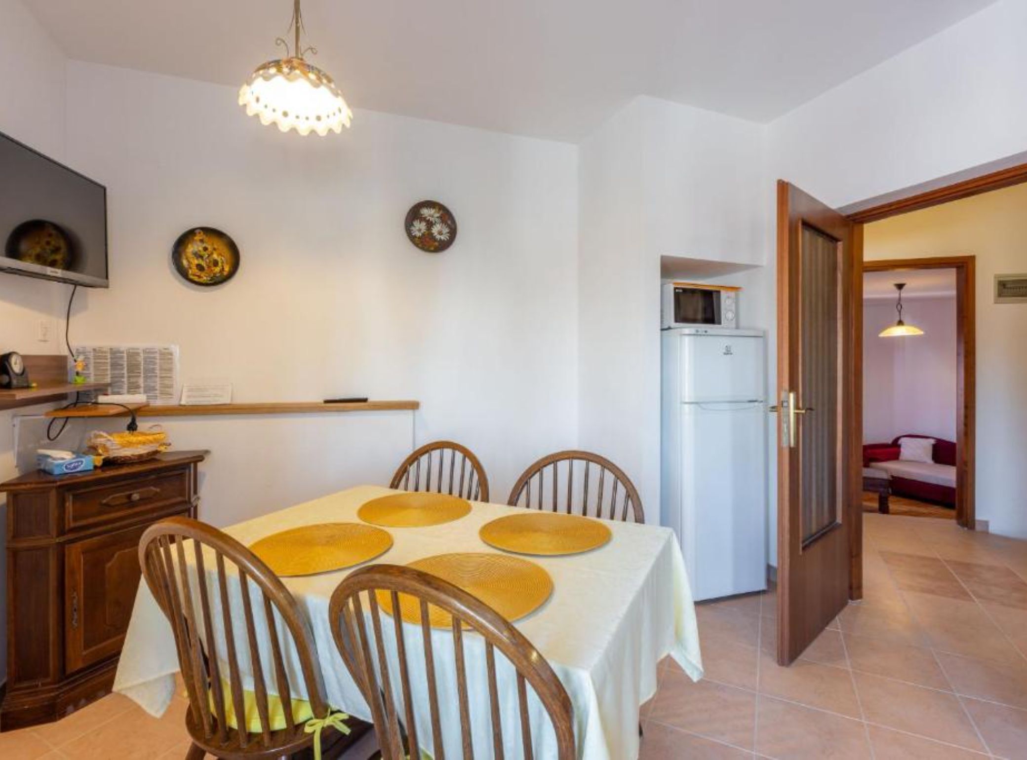 A dining area with a table, chairs, a refrigerator, and a microwave.