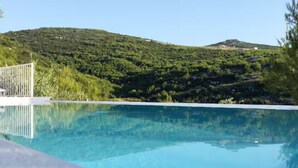 A clear blue swimming pool with a view of green hills in the background. - Villa Solea (Hvar)