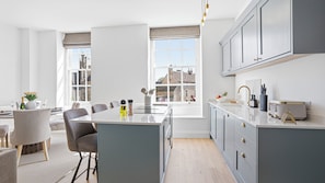 Una cocina moderna con una isla central, armarios grises y vistas a la ciudad a través de amplias ventanas.