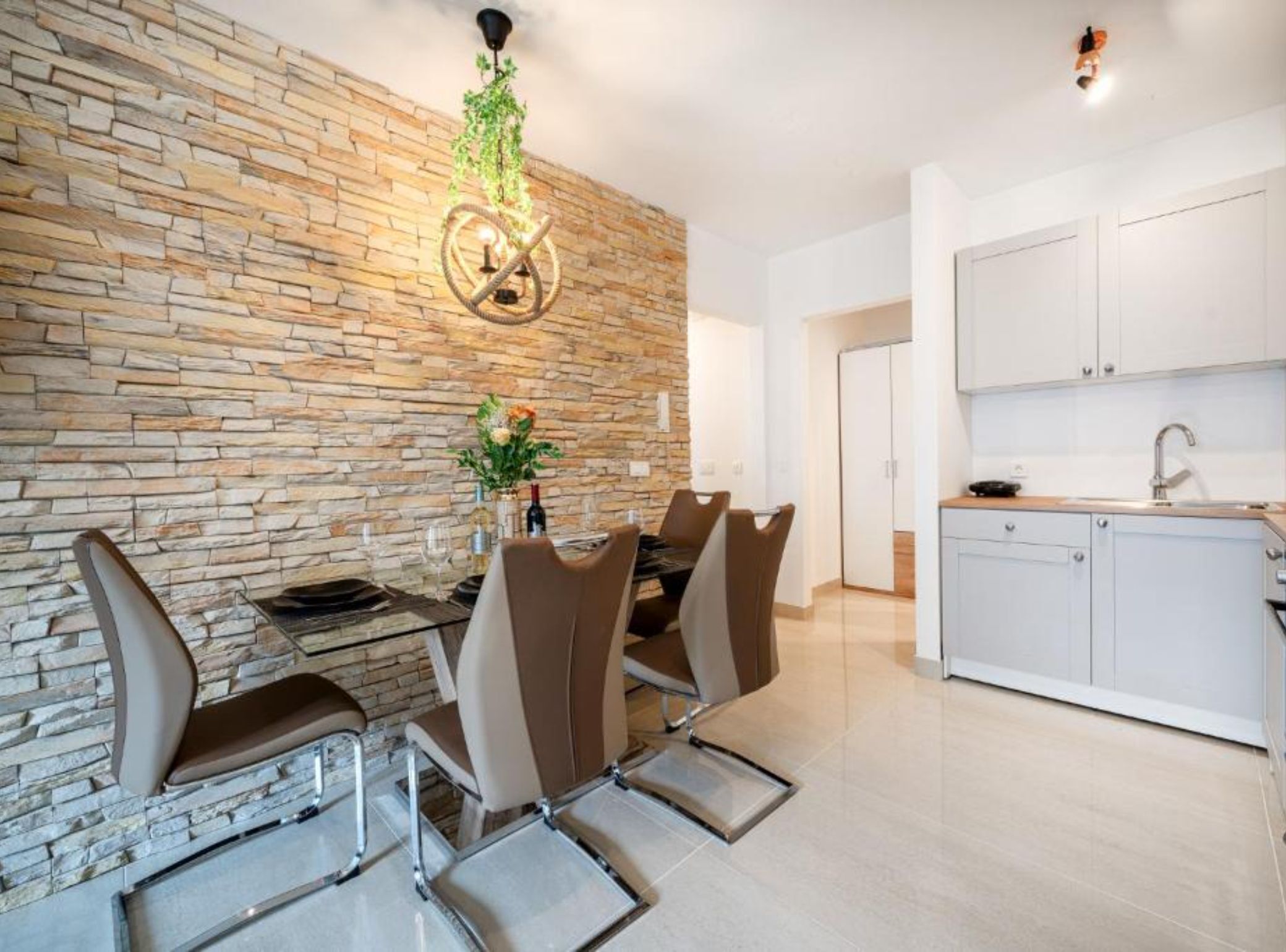 A dining area with a stone wall, a chandelier, and a table set for four.