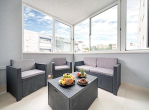 Ein Balkon mit Korbmöbeln, einem Tisch mit Obst und Blick auf die Stadt.