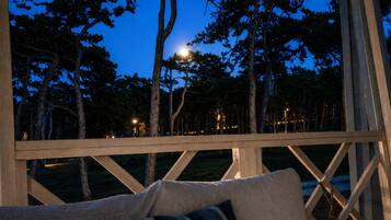 A wooden deck with a view of trees and a distant light source.