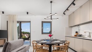 A modern kitchen with a dining area, a sofa, and a view of the outdoors. - Apartments Villa Mara With Pool (Omisalj)