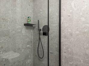 A shower with a handheld showerhead and a bottle of shampoo on a shelf. - Apartments Villa Mara With Pool (Omisalj)