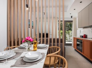Una cocina moderna con comedor, persianas verticales de madera y vistas a zonas verdes.