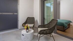 A modern room with a large sliding glass door, two wicker chairs, a small round table with a bottle and fruit, and a bed with a green cover. - Apartments Villa Mara With Pool (Omisalj)