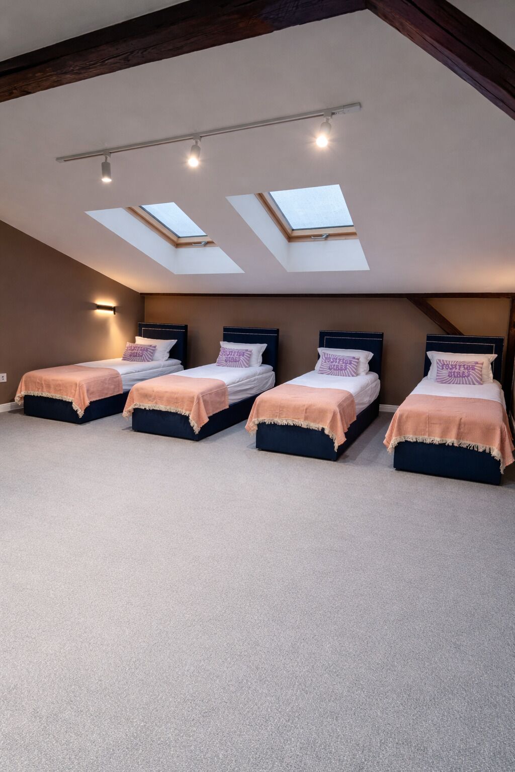 A bedroom with four beds, skylights, and a carpeted floor.