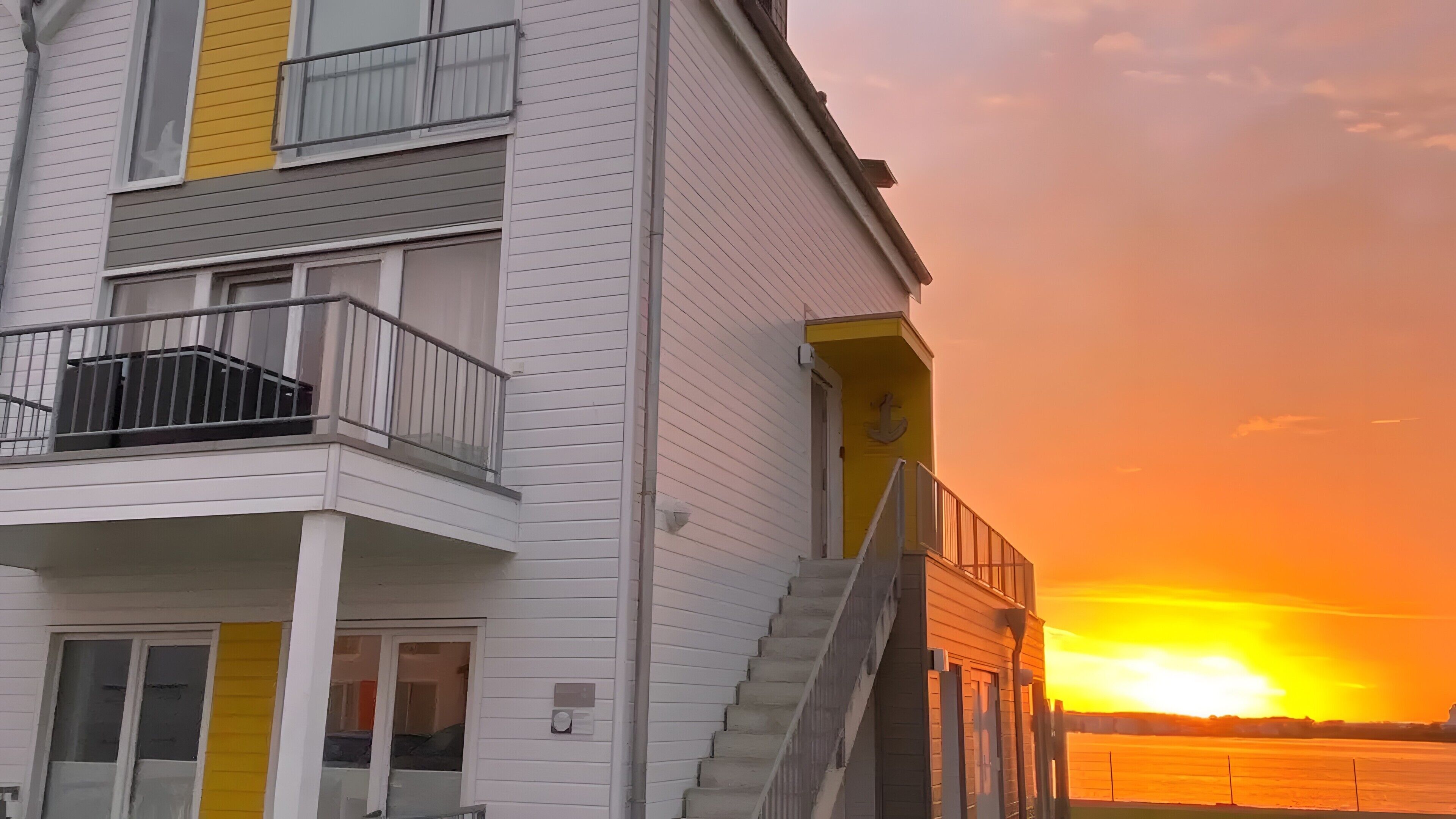 Een meerhoog gebouw met een balkon, een trap en uitzicht op de zonsondergang.