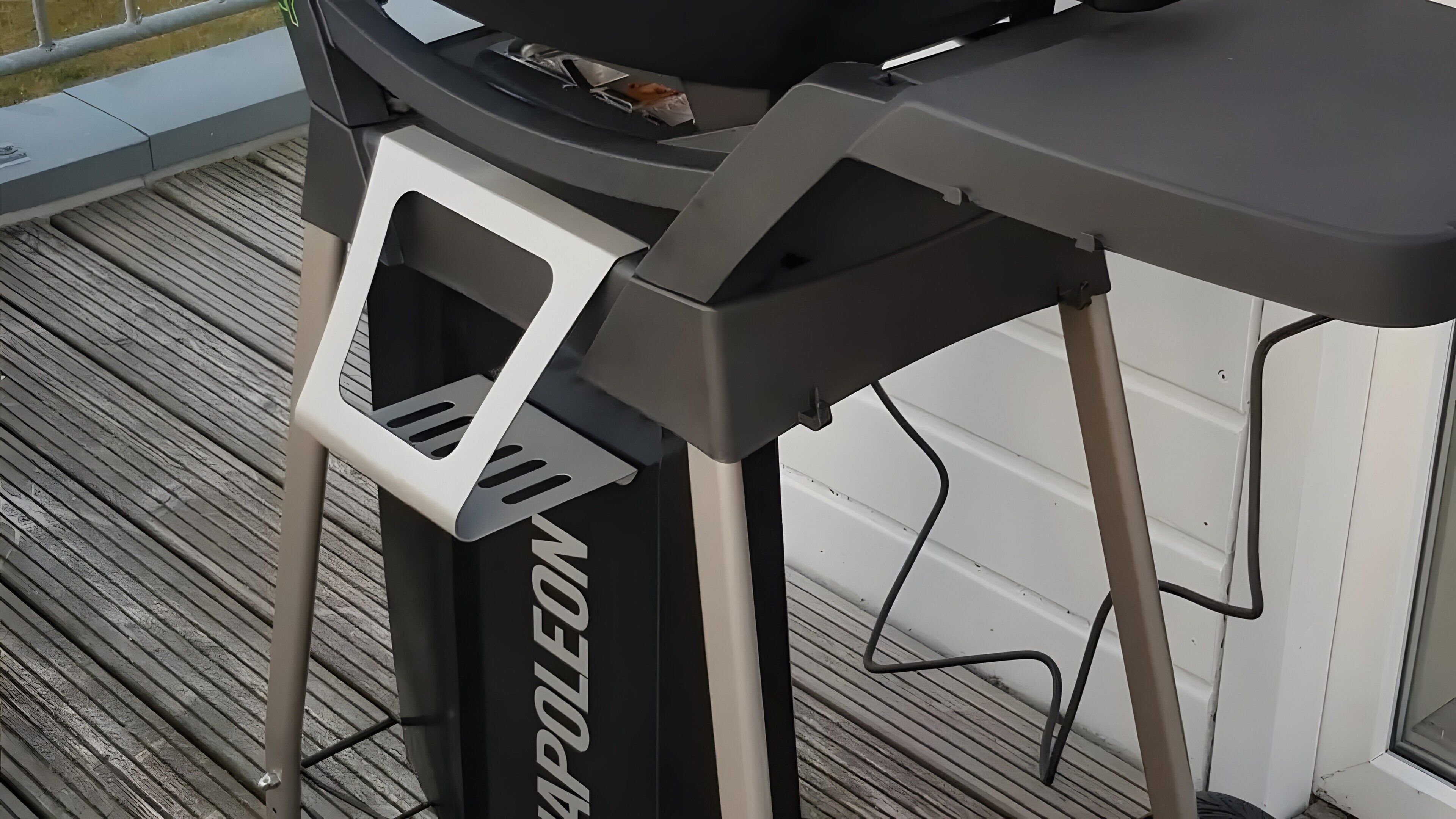 A barbecue grill with a white and black design, positioned on a wooden deck.