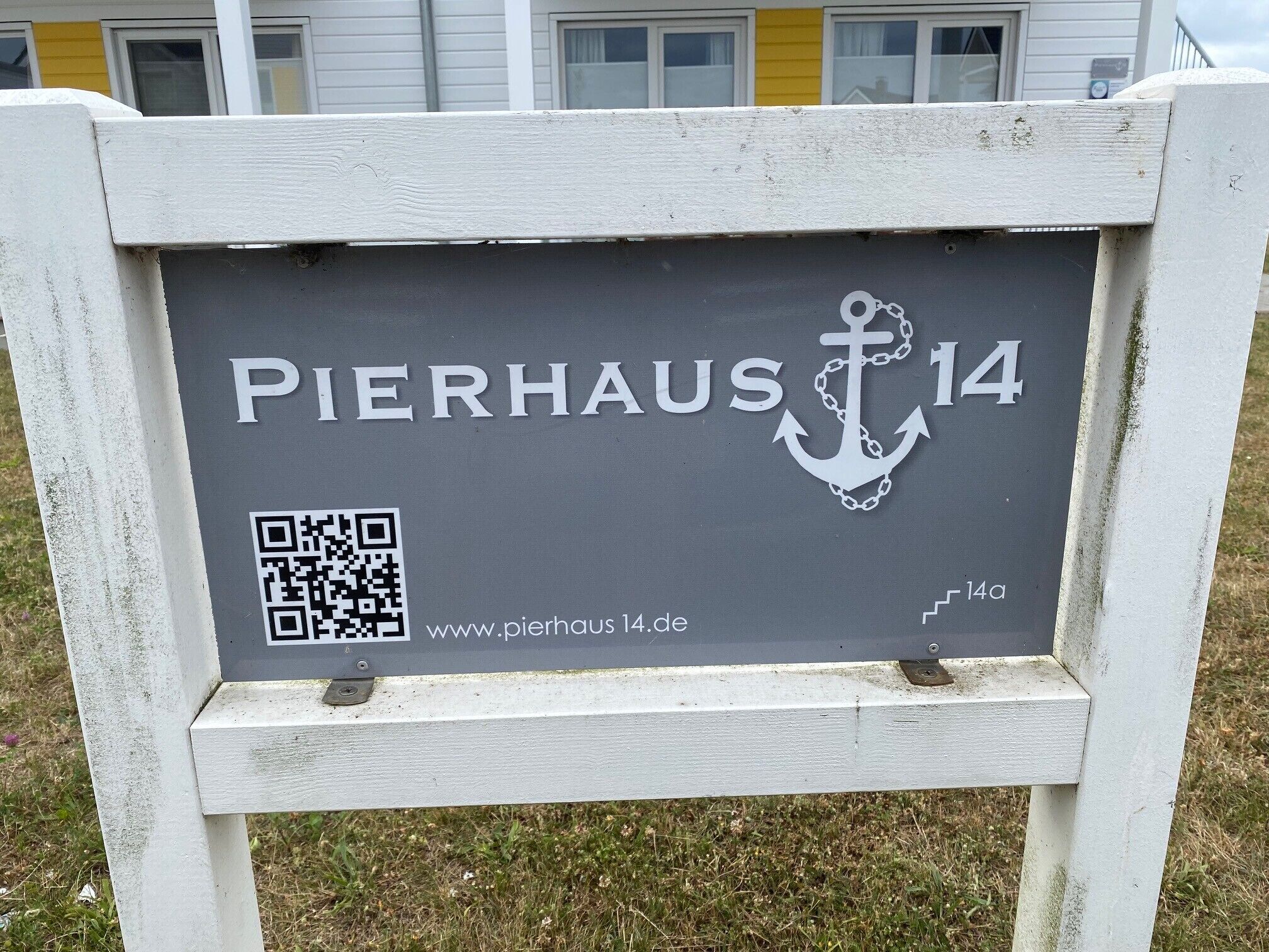 Une enseigne portant l’inscription « PIERHAUS 14 » et un code QR, indiquant le nom d’un hôtel et, éventuellement, son site web.