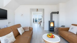 A modern living room with a fireplace, two sofas, a coffee table with fruit, and a TV. - Nothing Beats the Sea – 2-Bedroom Apartment for 5 with Harbor View in Kappeln (Kappeln)
