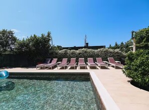 A pool area with clear water, surrounded by lounge chairs and greenery. - Deluxe Apartment Marghareta (Dubrovnik)