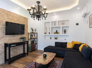 A living room with a flat-screen TV, a fireplace, a sofa, and decorative shelves. - Deluxe Apartment Marghareta (Dubrovnik)