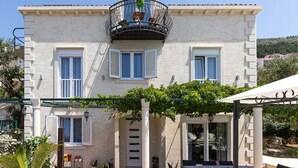 A two-story building with a balcony, a covered patio area, and a garden. - Deluxe Apartment Marghareta (Dubrovnik)