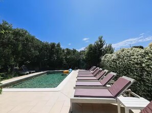 A pool area with lounge chairs and a clear pool. - Deluxe Apartment Marghareta (Dubrovnik)