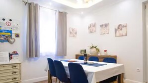 A dining area with a table set for four, blue chairs, and a white tablecloth. - Deluxe Apartment Marghareta (Dubrovnik)