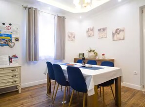 A dining area with a table set for four, blue chairs, and a white tablecloth. - Deluxe Apartment Marghareta (Dubrovnik)