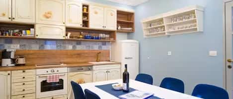Una cocina moderna con armarios blancos, encimera de madera y comedor con mesa y sillas.