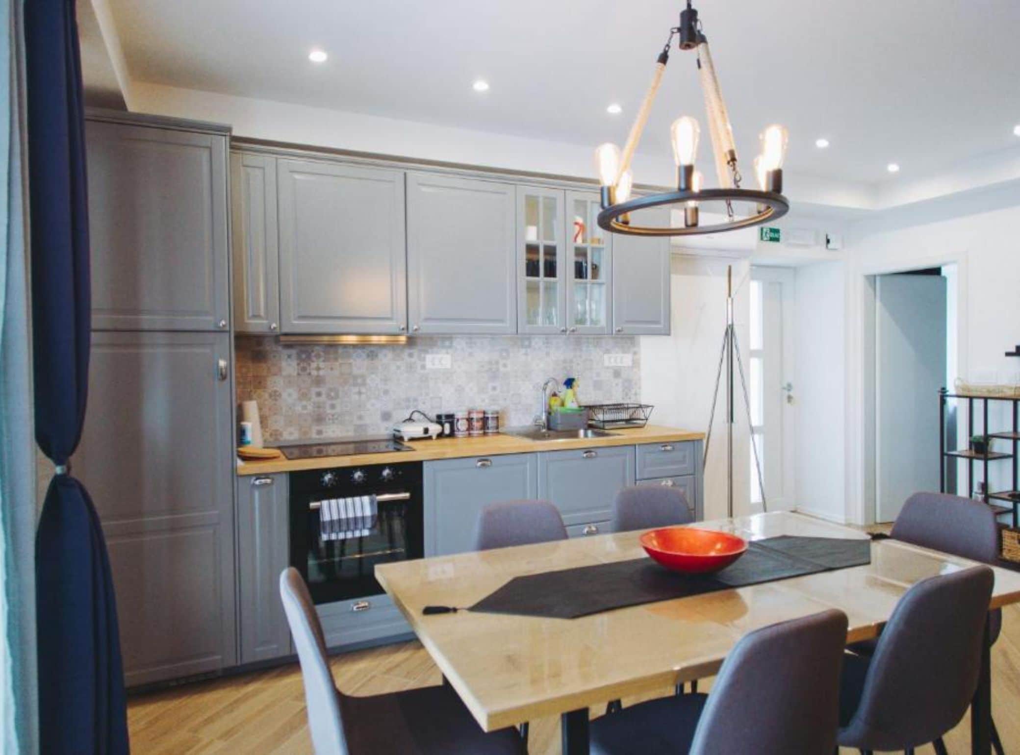 Una cocina moderna con armarios grises, encimera de madera y un comedor con mesa y sillas.