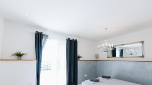 Un dormitorio con cama, candelabro, espejo y vistas al exterior.