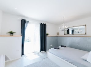 A bedroom with a bed, a chandelier, a mirror, and a view of the outdoors. - Residence Apartment Marghareta No. 2 (Dubrovnik)