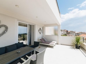 Un balcón con mesa y sillas, una decoración con forma de corazón y vistas de la ciudad.