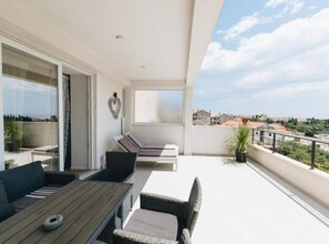 Ein Balkon mit Tisch und Stühlen, einer herzförmigen Dekoration und Blick auf Gebäude und Bäume.