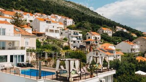 Una zona residencial con edificios en una colina, una piscina y un edificio moderno con balcón.