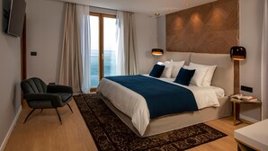 Ett modernt hotellrum med en stor säng, ett skrivbord, en stol och en TV.