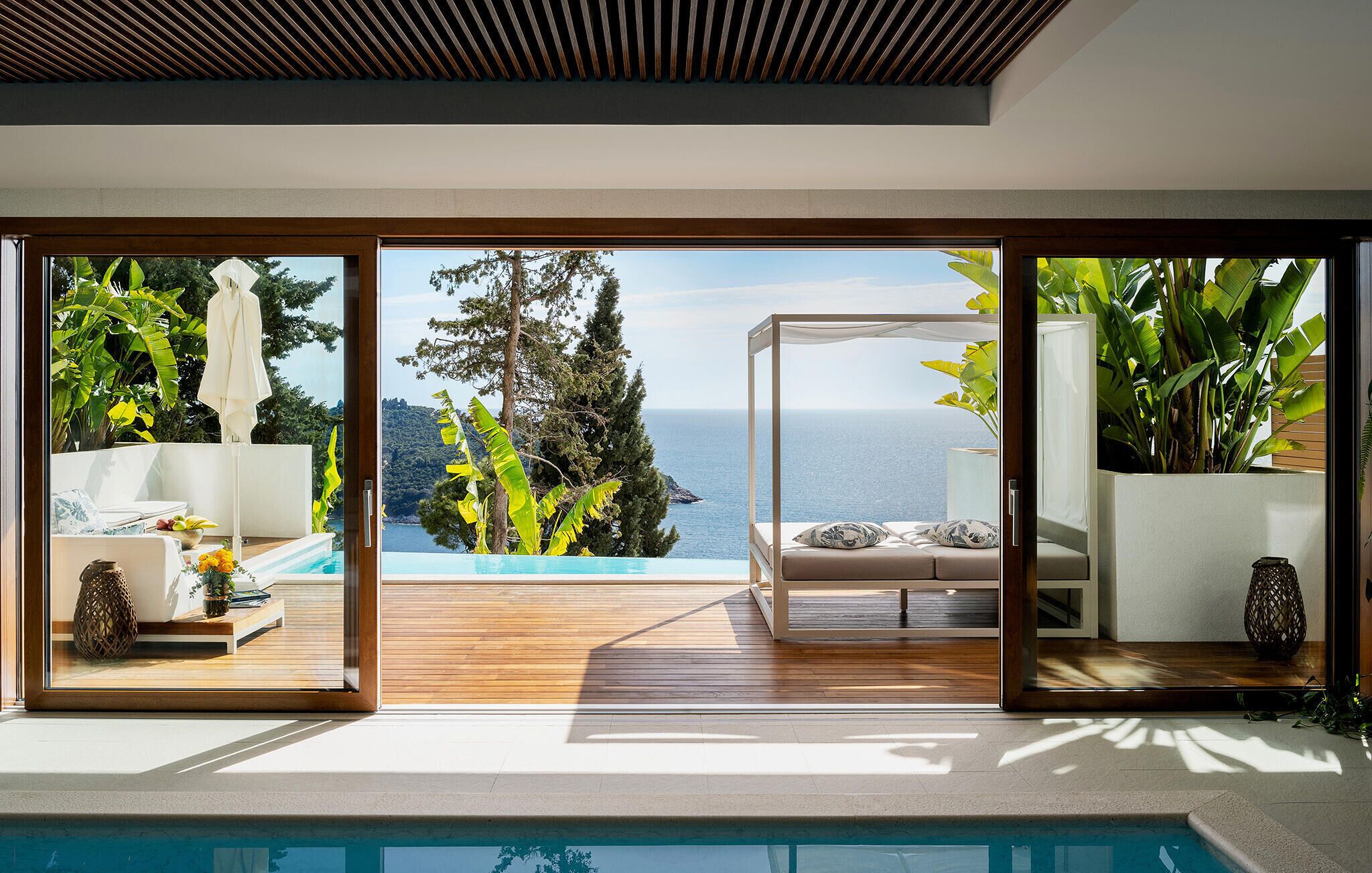 Ein moderner Balkon im Freien mit Pool, einer gemütlichen Sitzecke und Blick aufs Meer.