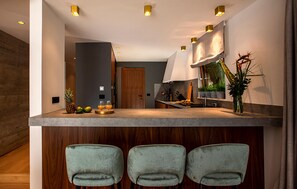 A modern kitchen with a bar area, wooden bar stools, and a large window with plants. - Awesome home in Dubrovnik with sauna (Dubrovnik)